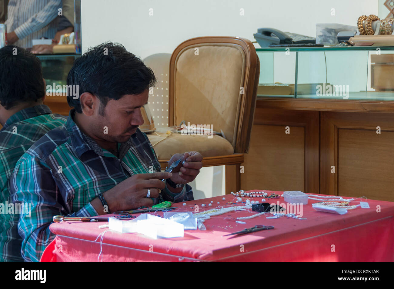 Ein indischer Juwelier stringing Perlen auf einer Perlenkette an einem der Hyderabad viele Schmuckgeschäfte. Hyderabad, Telangana, Indien. Stockfoto
