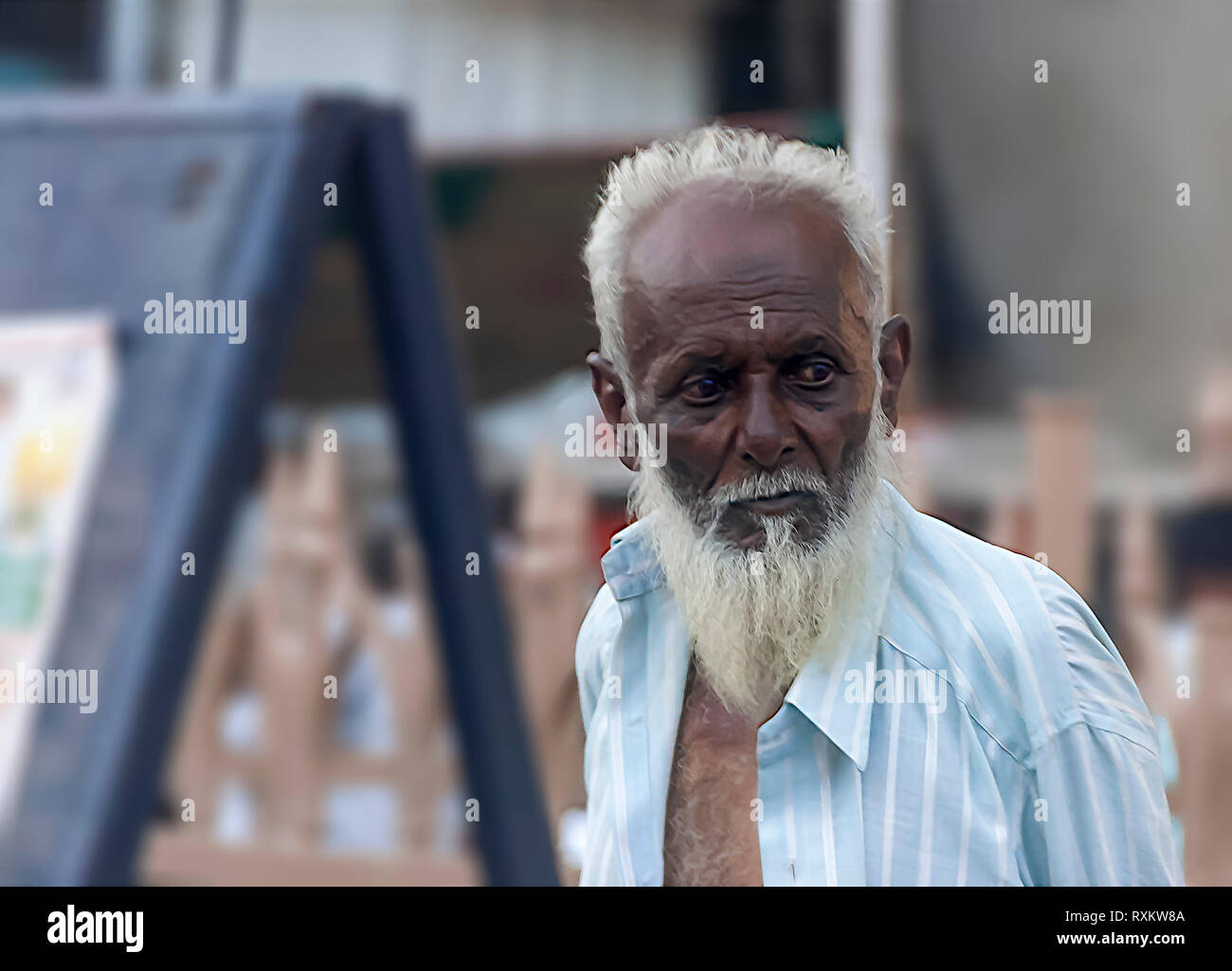 Ein muslimischer Mann, der sein Hemd öffnen sich in heißen Sommer Wetter etwas in der Ferne suchen zu kühlen. Hyderabad, Telangana, Indien. Stockfoto