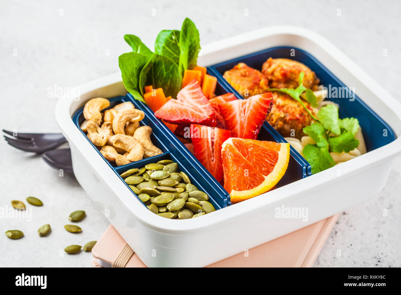 Gesundes Essen Lunch Box. Gesunde Mahlzeit prep Container mit Bohnen Frikadellen, Pasta, Gemüse, Beeren, Samen und Nüsse in einem Container auf einem weißen backgr Stockfoto