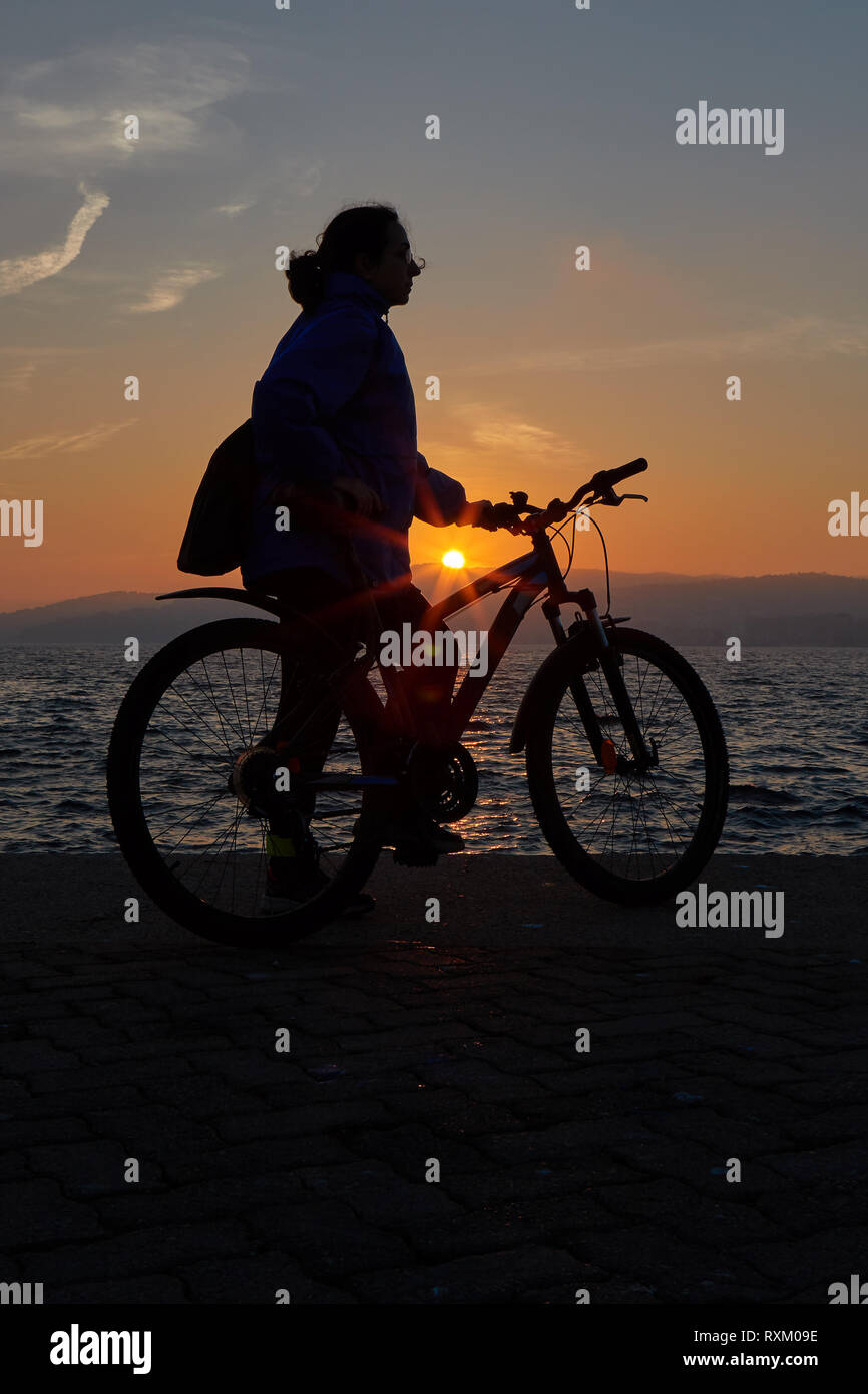 Pretty girl Silhouette mit dem Fahrrad in einen Sonnenuntergang Licht Stockfoto