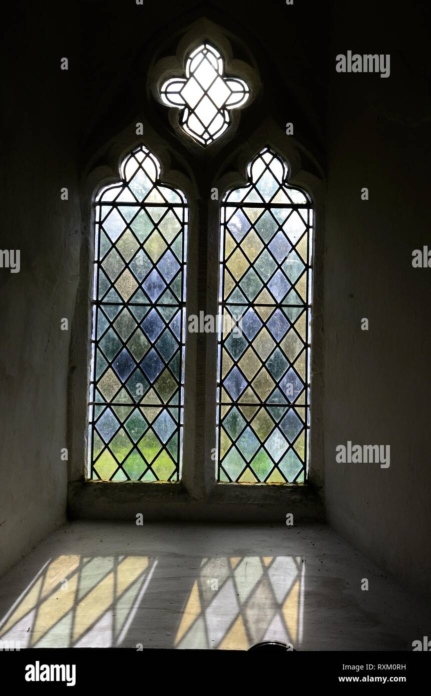 Licht scheint durch ein Glasfenster in der Kirche St Odoceus Llandawke Laugharne nun in der Obhut der Freunde ohne Freunde Kirchen Wales Stockfoto