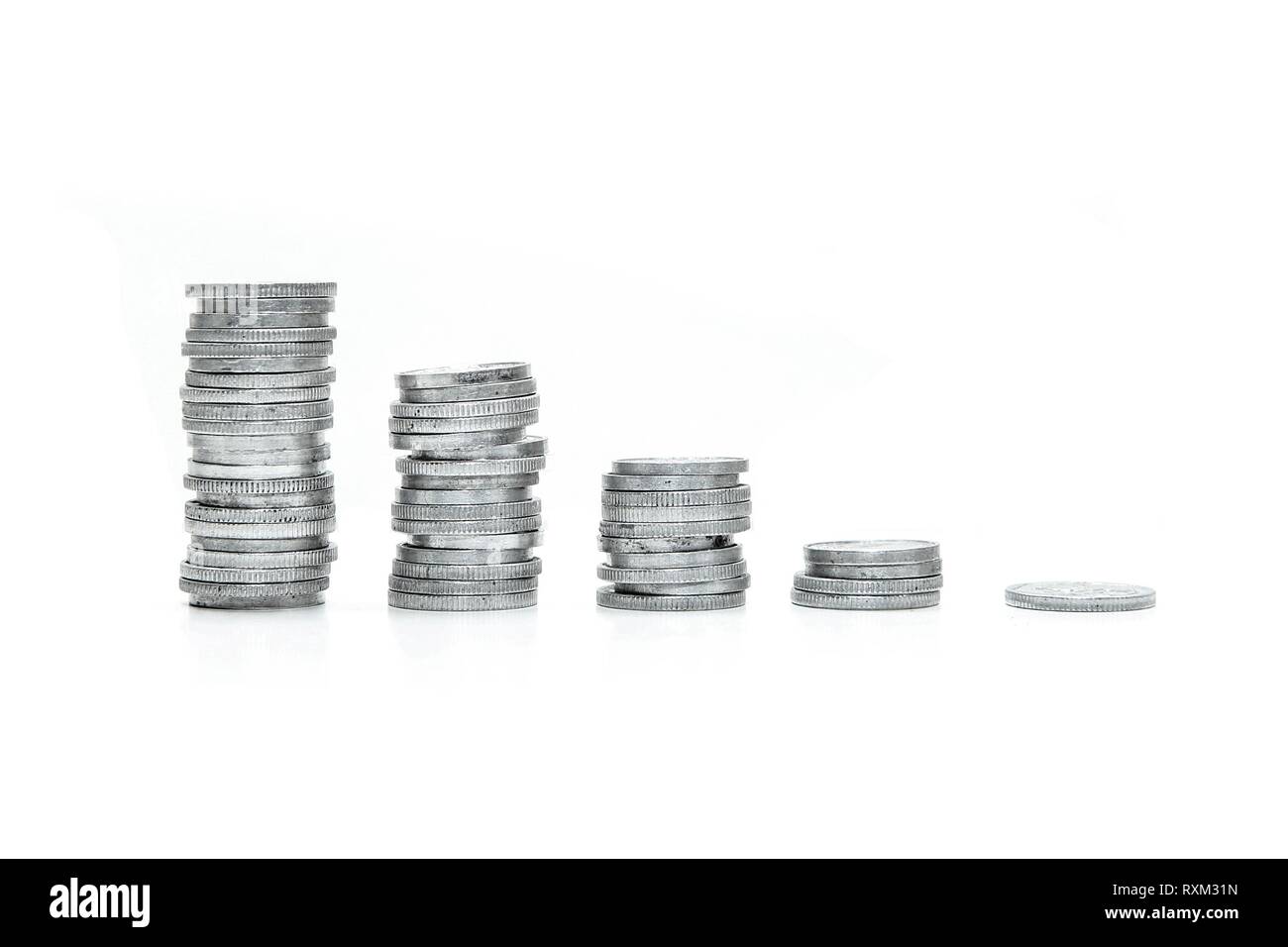 Eine Spalte mit kleinen Münzen von der höchsten zur niedrigsten sortiert. Symbolisiert den Rückgang der Preise. Auf weissem Hintergrund. Stockfoto