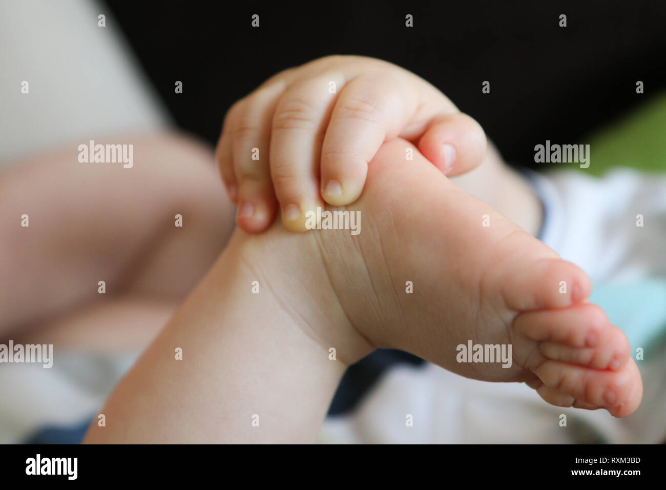 Ein Detail Foto von Händen und Füßen des Kindes. Das Kind hält seine Füße und Erforschen ihrer Körper und die Ausbildung seiner Fähigkeiten. Stockfoto