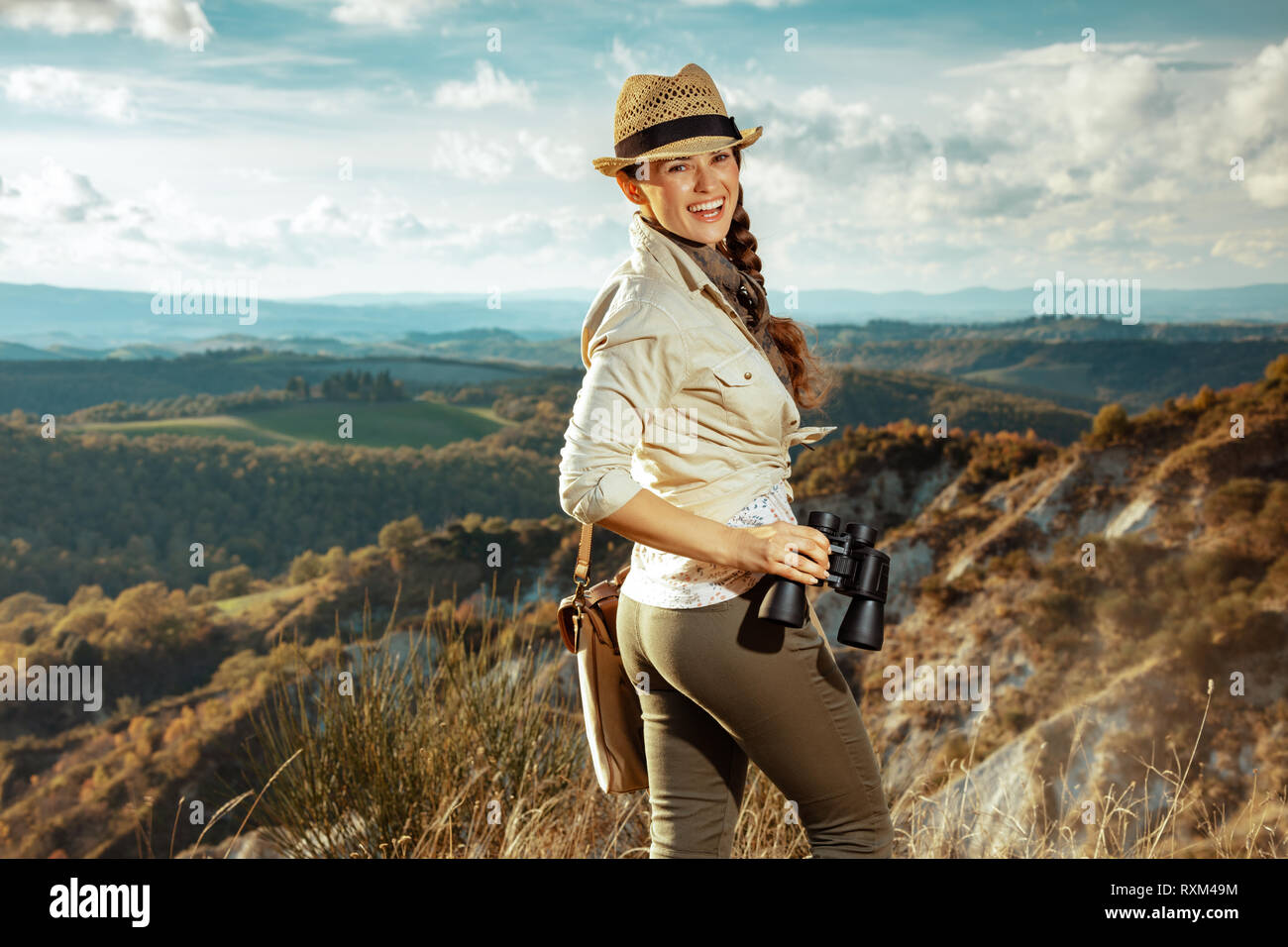 Glückliche junge Reisende Frau in Wanderausrüstung mit Tasche mit Fernglas genießen Sie im Sommer die Toskana. Stockfoto