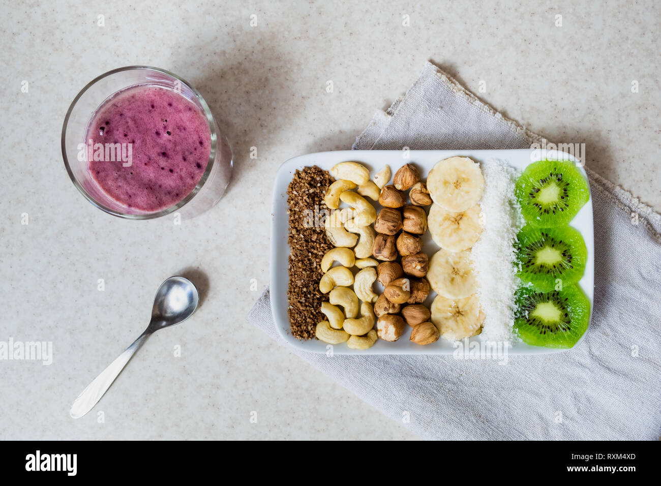 Frische Zutaten für eine gesunde Rohkost Frühstück. Kiwi, Kokosraspeln, Cashews und Haselnüsse Schuß von oben, Zutaten für einen Smoothie Schüssel Stockfoto