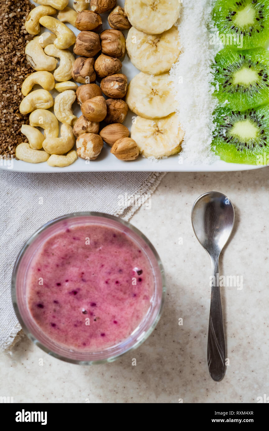 Frische Zutaten für eine gesunde Rohkost Frühstück und Smoothie Schüssel. Kiwi, Kokosraspeln, Cashews und Haselnüsse Schuß von oben, Zutaten für Aca Stockfoto