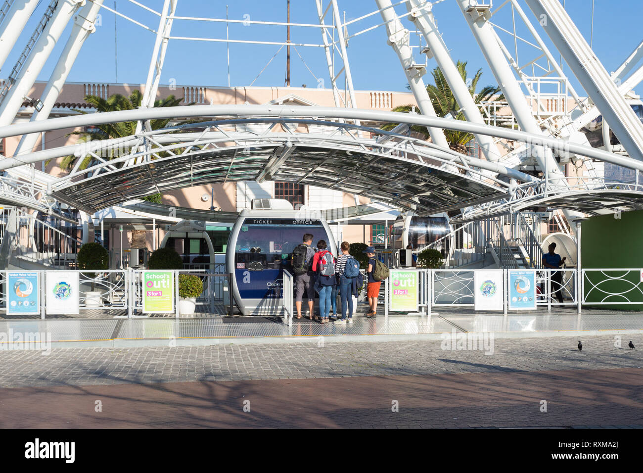 Familie Schlange an der Kasse von Riesenrad Tickets auf einer Fahrt an der V&A Waterfront, Kapstadt, Südafrika im Winter bei Sonnenuntergang zu kaufen Stockfoto