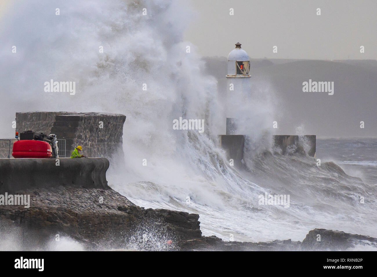 Wellen gegen die hafenmauer als Arbeitnehmer arbeiten am Meer Verteidigung während eines Sturms auf Porthcawl, Wales durchführen. Das Met Office haben einen gelben w ausgestellt Stockfoto