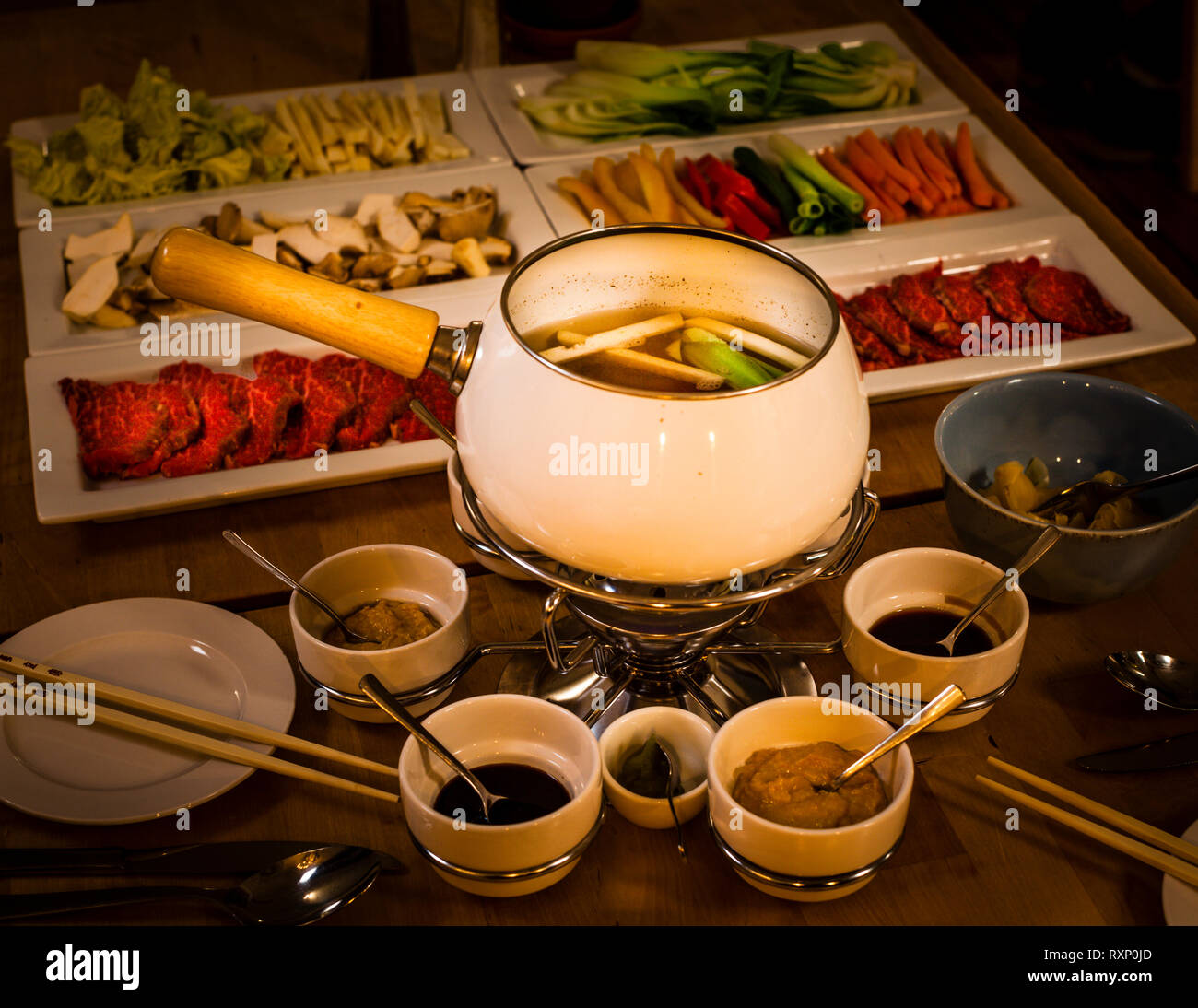 Ein japanisch-mecklenburgisches Fondue ist auf dem Tisch im Restaurant des Kavaliershauses Schloss Blücher in Fincken, Deutschland, angerichtet: zartes regionales Rindfleisch wird von den Gästen selbst in einer leichten Misosuppe gekocht, begleitet von einer großen Auswahl an Gemüse sowie Ponzu-, Soja- und Sesamsoßen zum Würzen. Die Speisekarte nennt das Gericht „Ja-Panisch trifft Ja-Mecklenburgisch“ ("Ja-Panese trifft Ja-Mecklenburg"). Stockfoto