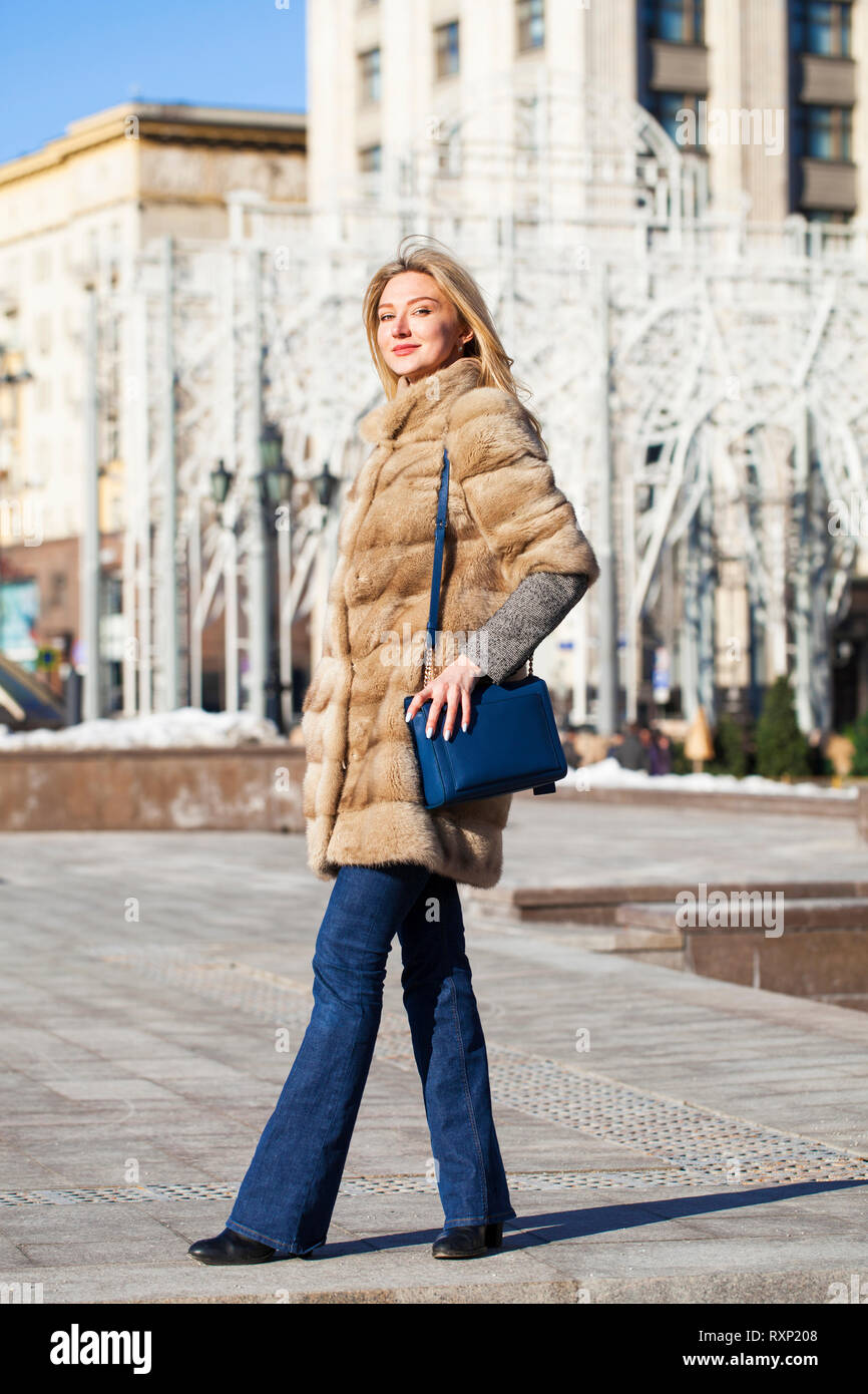 Porträt einer vollen Länge junge blonde Frau im Nerz winter Fell und blaue Jeans, draußen im Herbst Straße Stockfoto