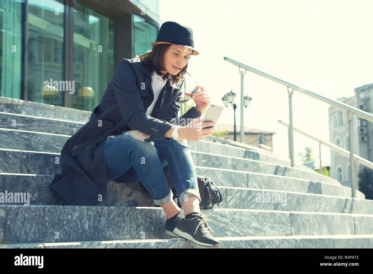 Outdoor Portrait einer stilvollen Frau in Hut und Sonnenbrille mit Smartphone Stockfoto