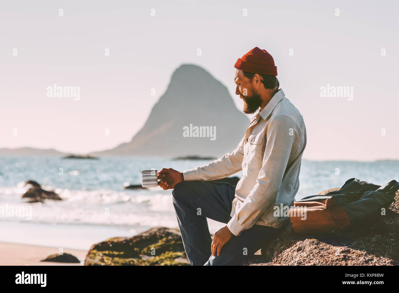Mann Entspannung am Meer Strand holding Tee Tasse solo Reisen lifestyle Abenteuer Sommer Ferien in Norwegen das Frühstück im Freien Stockfoto