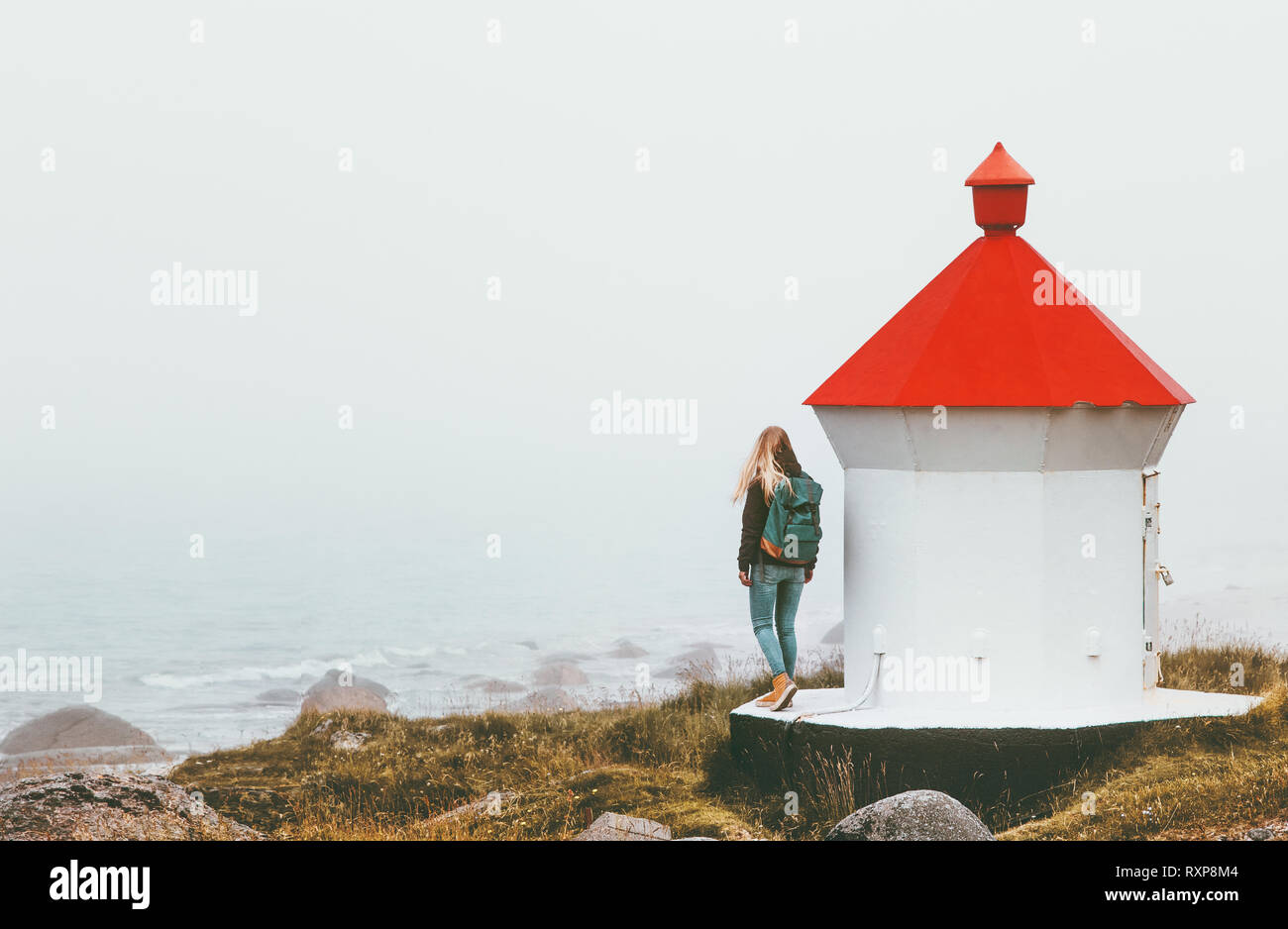 Reisende Frau in der Nähe von Leuchtturm genießen foggy Meerblick solo Reisen Lifestyle reise Abenteuer outdoor Einsamkeit Gefühle Stockfoto