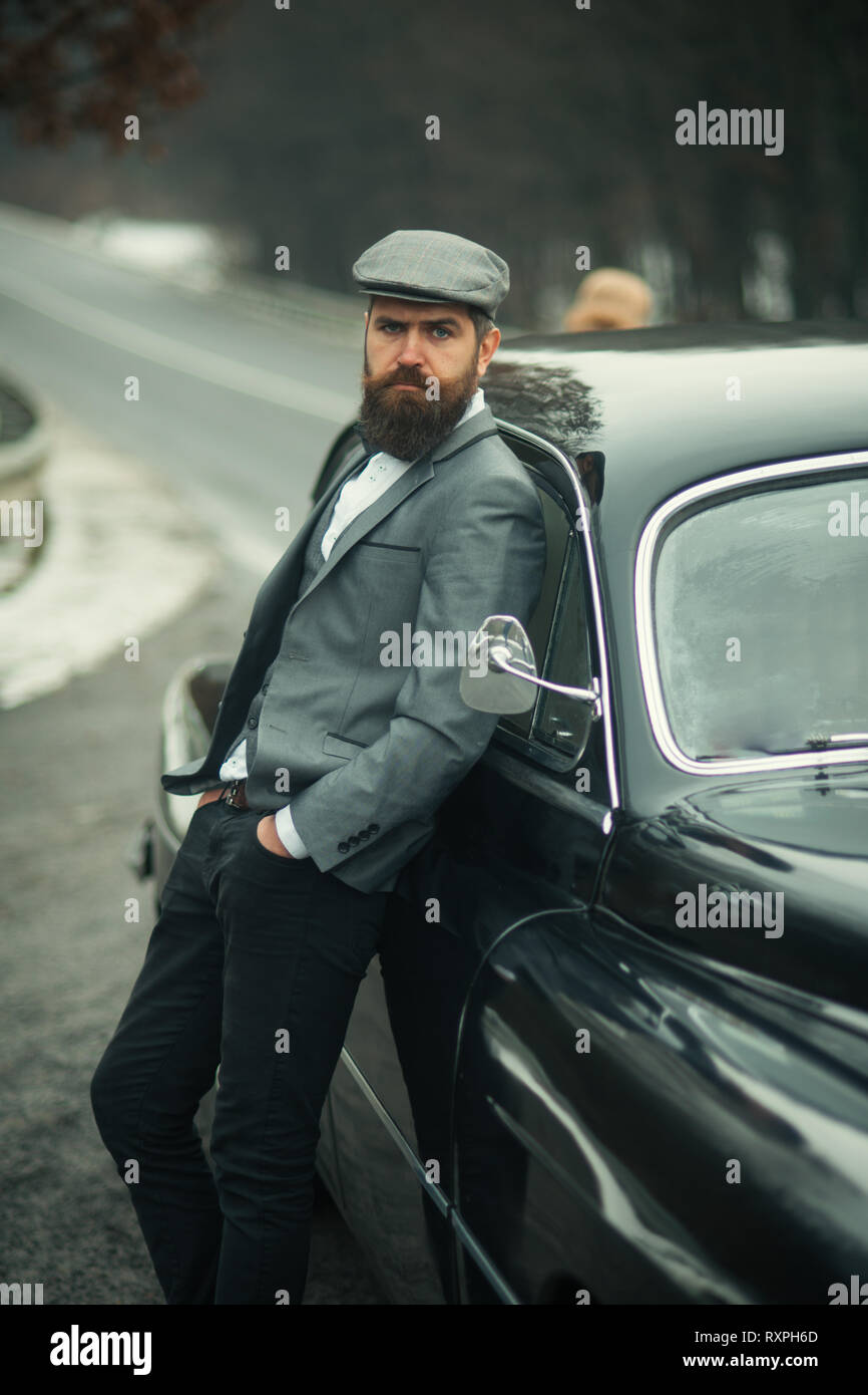 Geschäftsmann in Anzug und Kappe an retro Auto. Geschäftsmann auf der Straße. Stockfoto