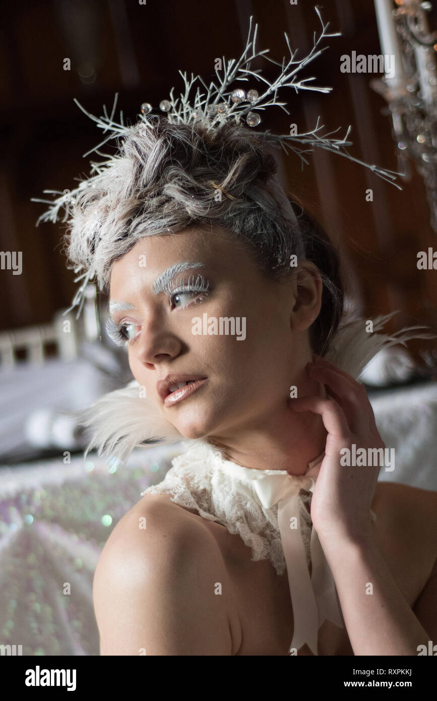 Eine schöne kaukasische Mädchen in einem langen weißen Kleid stellt sich dramatisch im gotischen Stil für einen redaktionellen Foto schießen. Das Thema ist Wintermärchen. Stockfoto