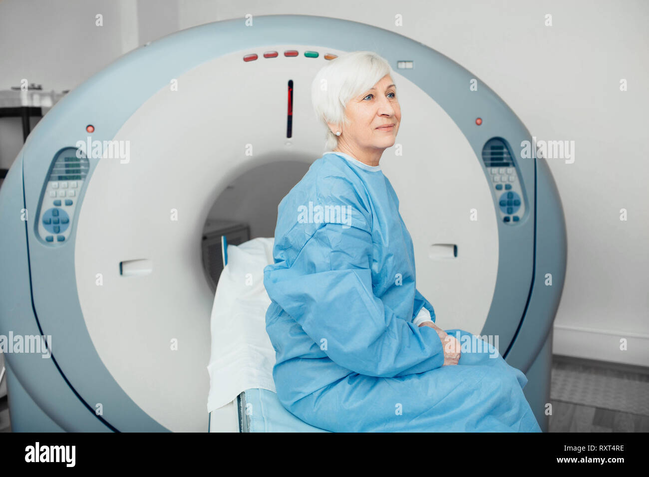 Nachdenklich, ältere Frau sitzt auf der scanner Tabelle. Warten auf CT-Scan Stockfoto