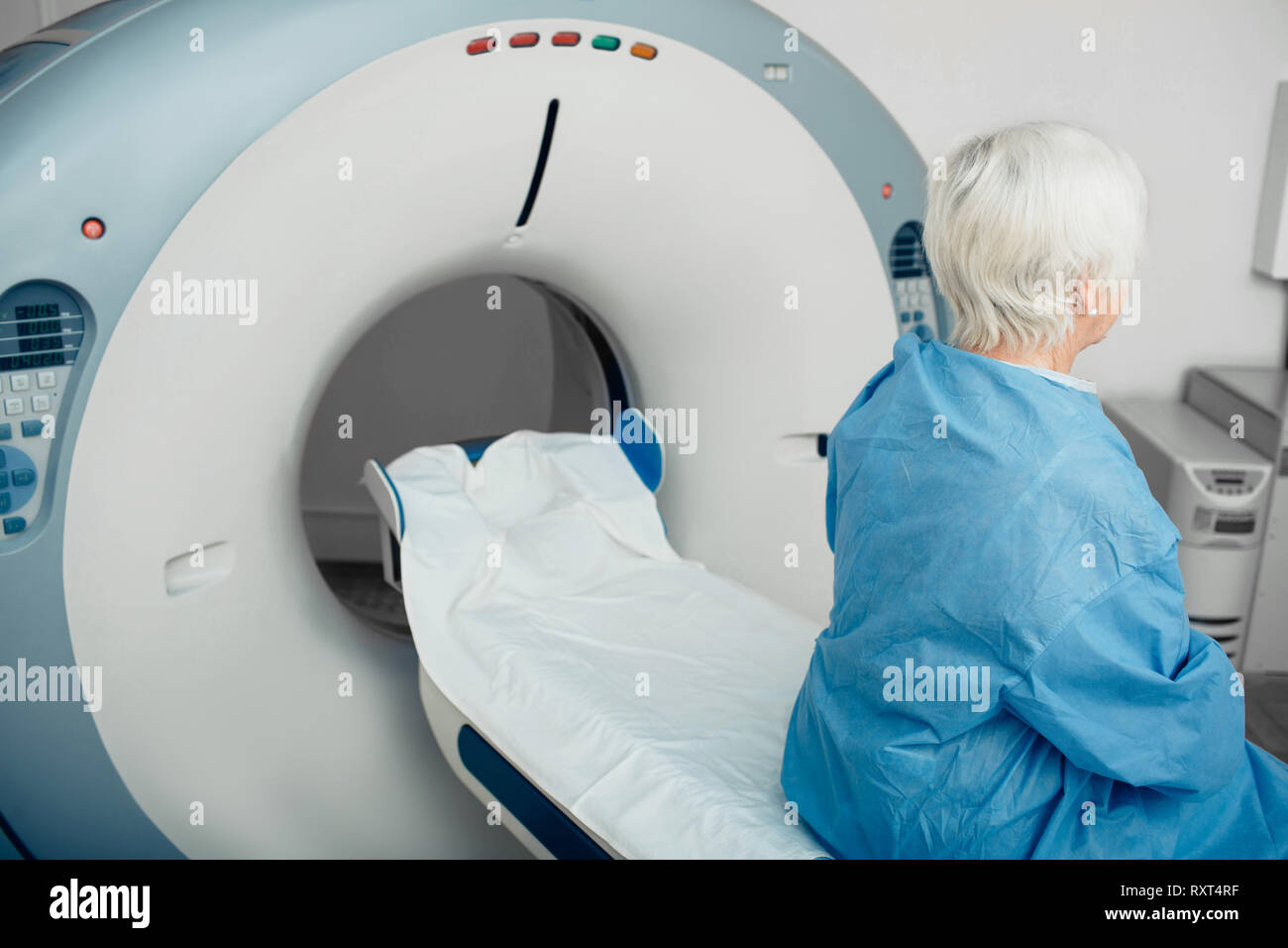 Nachdenklich, ältere Frau sitzt auf der scanner Tabelle. Warten auf CT-Scan Stockfoto