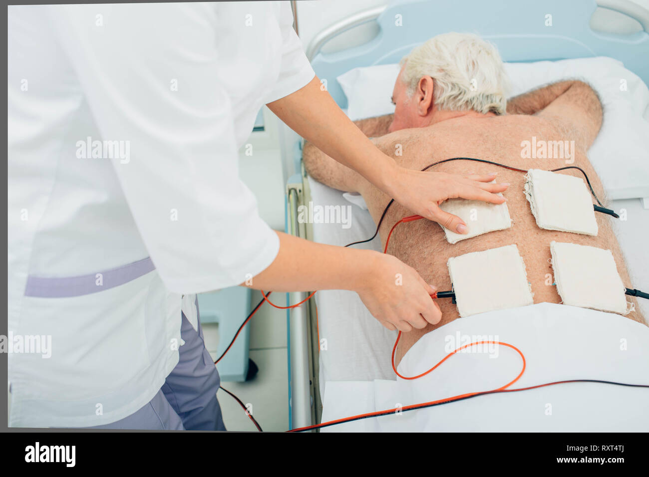 Die physiotherapeutische Behandlung. Ältere Patienten mit Ultraschall und Elektrotherapie Behandlung auf seinem Rücken Stockfoto