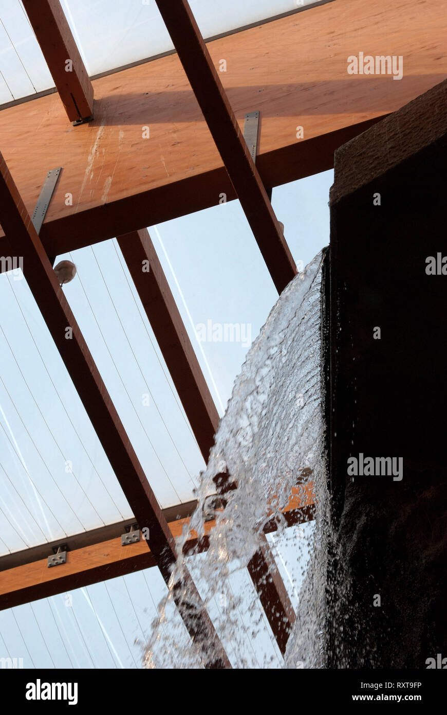 Fragment der Struktur im Africarium. Das Wasser des künstlichen Wasserfall ist sichtbar. Sichtbar Vogel auf dem Balken unter der Decke. Stockfoto