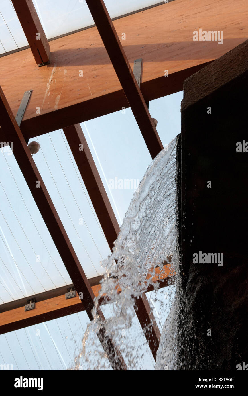Das Wasser des künstlichen Wasserfall ist sichtbar. Fragment der Struktur im Africarium. Sichtbar Vogel auf dem Balken unter der Decke. Stockfoto