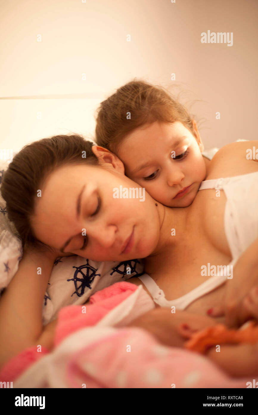 Glückliche Mutter im Bett mit Tochter und Neugeborene Stockfoto