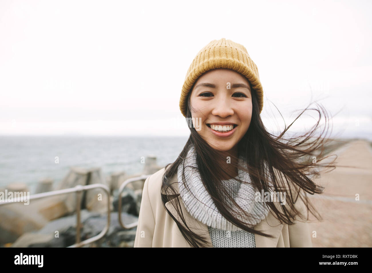 Nahaufnahme von einem lächelnden Frau im Winter tragen, stehen in der Nähe des Meeres. Asiatische Frau, die draußen an einem kalten Wintermorgen. Stockfoto