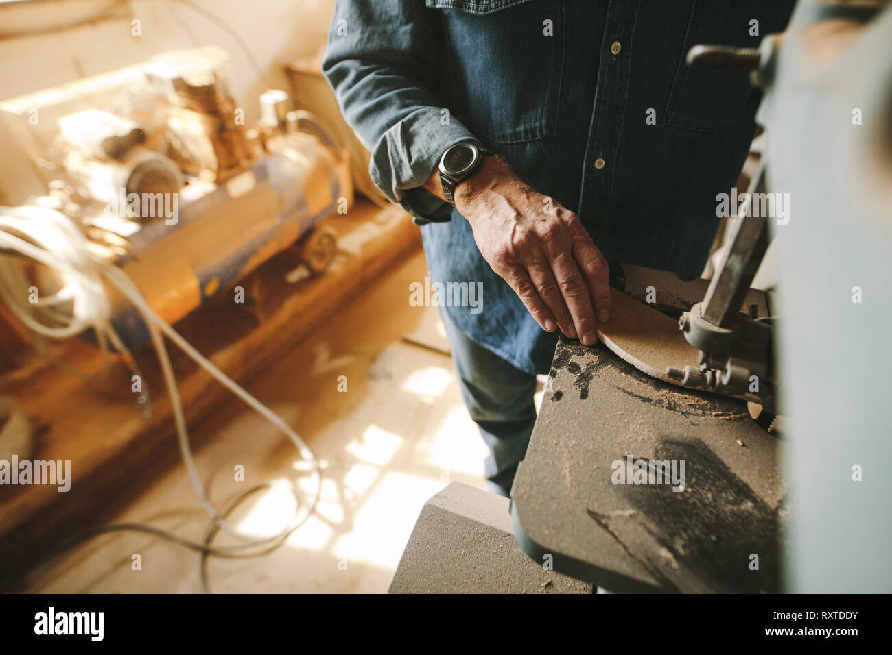 Mitarbeiter in der Schreinerei Schnitte und Formen den Wald mit Band gesehen. Fokus auf Tischler Hand in der Schreinerei arbeiten. Stockfoto