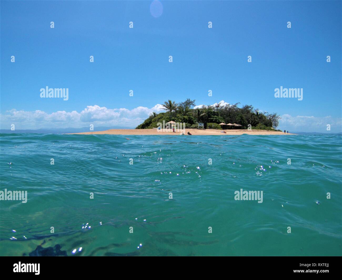 Niedrige Insel von Port Douglas mit klaren, blauen Meer im Vordergrund und reinen Himmel im Hintergrund. Stockfoto