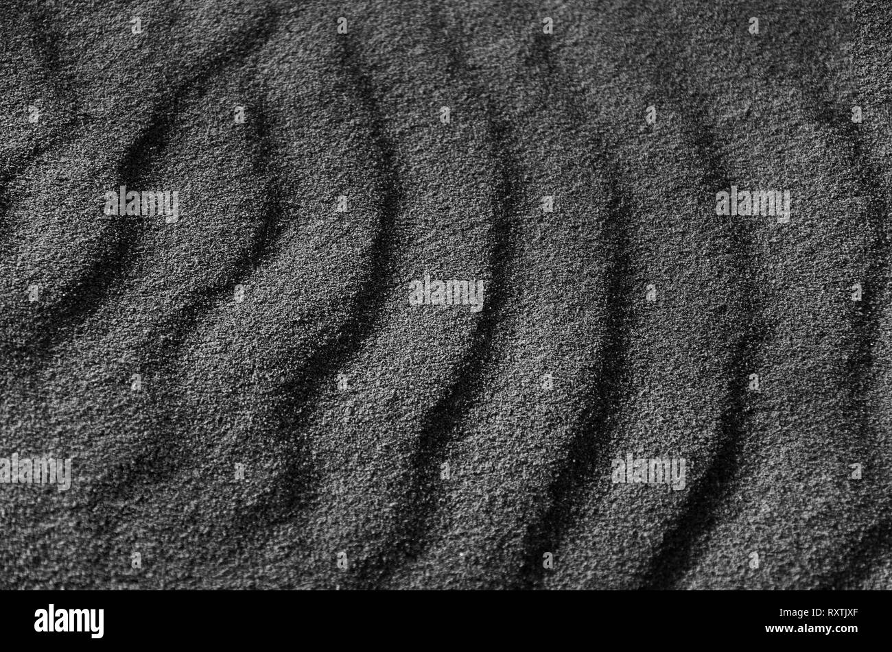 Monochromatische Photographie des Sand im Meer, abstrakte grauer Hintergrund, dunkle Linien Muster, körnige Struktur Stockfoto
