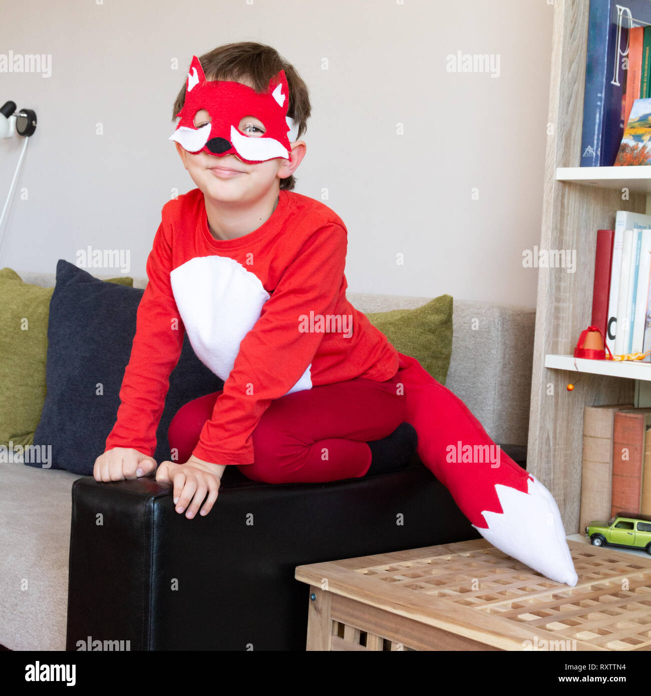 Kind in Fox fancy dress Maske sitzt auf einem Sofa imitieren eine echte Fox Stockfoto
