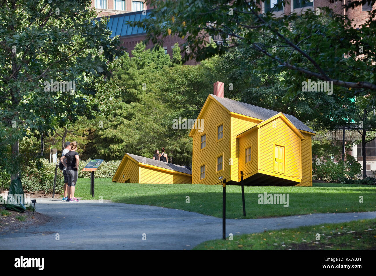 Gelbes Haus teilweise in den Rasen durch Künstler Mark Reigelman versenkt und mit dem Titel "Haus der Begegnung" in der Rose Kennedy Greenway, Boston, Massachusetts, USA Stockfoto