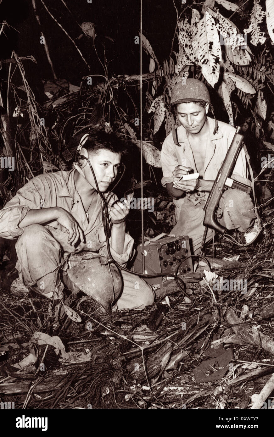 Navajo code talkers Corporal Henry Backen, jr., (links) und Private First Class George Kirk (rechts), mit einem Marine Signal Unit, Betrieb eines tragbaren Radio in einem Clearing sie gerade im dichten Dschungel dicht hinter der Front auf der Insel Bougainville in Papua Neuguinea haben während des Zweiten Weltkrieges im Dezember 1943 gehackt. Stockfoto