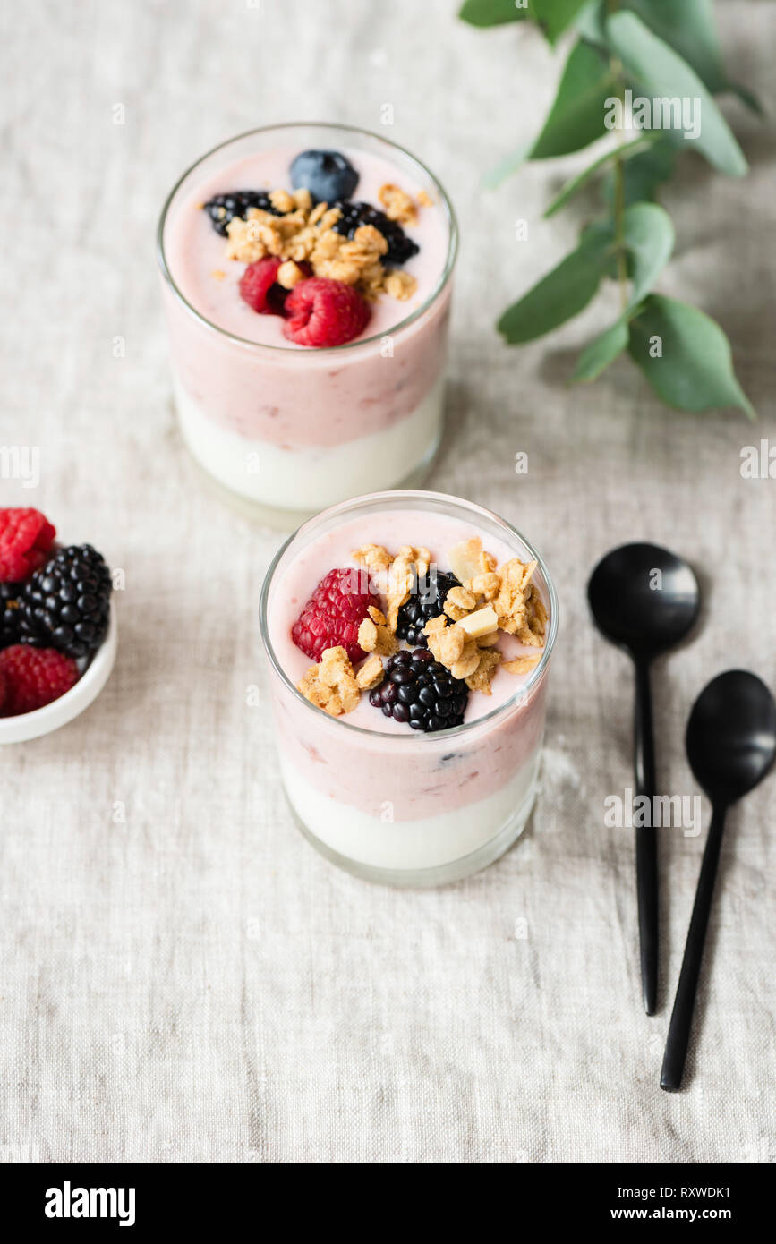 Joghurt mit Beeren und Müsli in Glas Schale auf Leinen Hintergrund. Minimalistischer Stil Foto von gesunden vegetarischen Frühstück Stockfoto