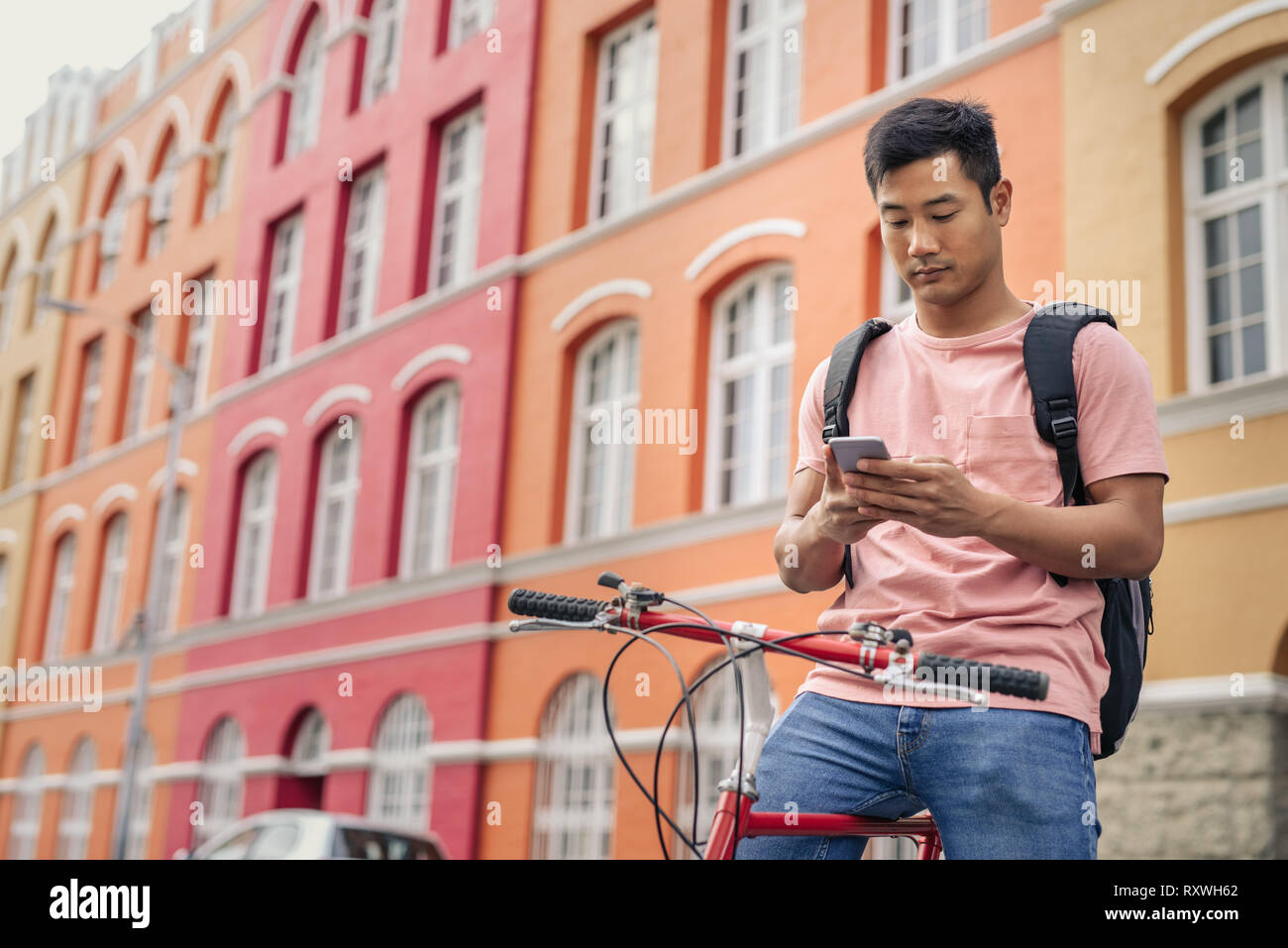 Jungen asiatischen Mann sitzt auf seinem Fahrrad eine sms senden Stockfoto