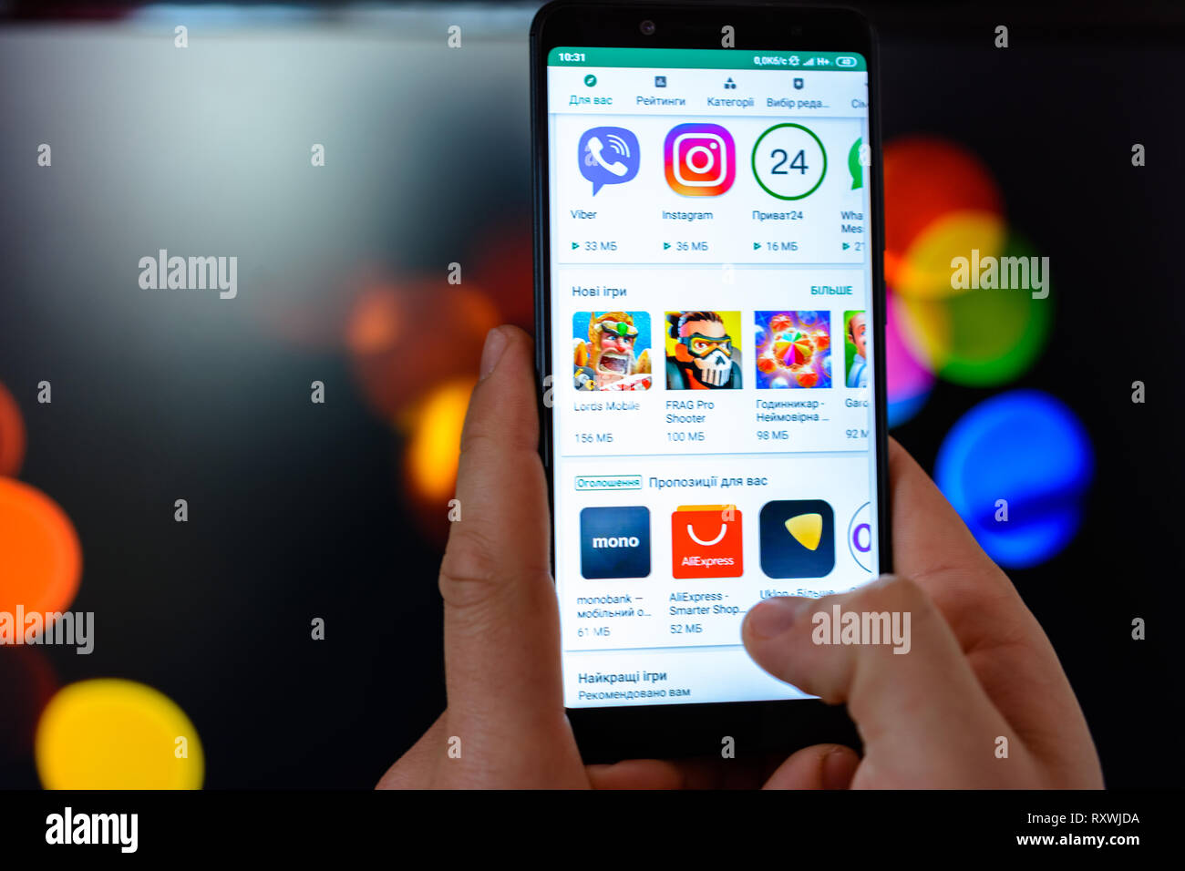 Lemberg, Ukraine - MÄRZ 09, 2019: Der Mann hält das Smartphone in seinen Händen zu schließen und die Anwendung wird geöffnet und Sie können das Google Spiel auf einem verschwommenen Hintergrund Stockfoto