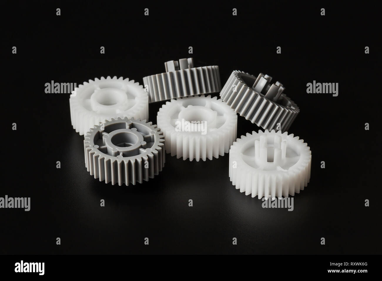 Drei graue und drei weißen Kunststoff-zahnrädern auf einem dunklen Hintergrund closeup Stockfoto