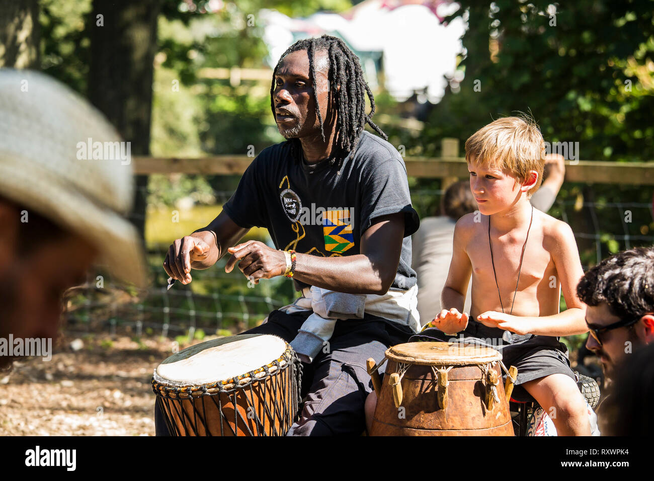 Festivalbesucher teilnehmen einen Trommelworkshop in den Wäldern auf in die Wildnis Festival, Kent, Großbritannien Stockfoto