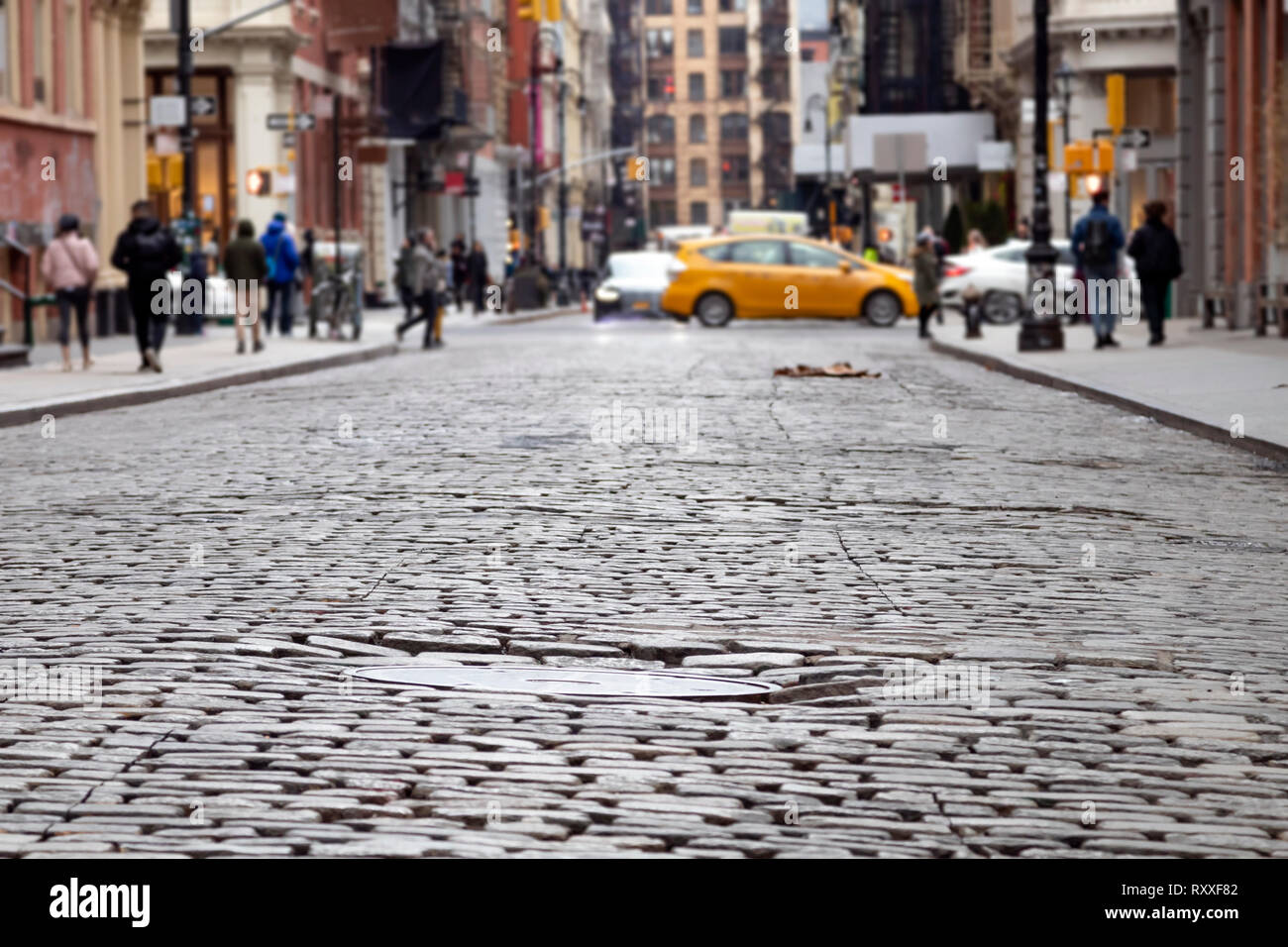 Straße mit Kopfsteinpflaster auf der vielbefahrenen Kreuzung von Broome und Greene Straßen mit Menschen und Taxi im Viertel SoHo in Manhattan in New York C Stockfoto