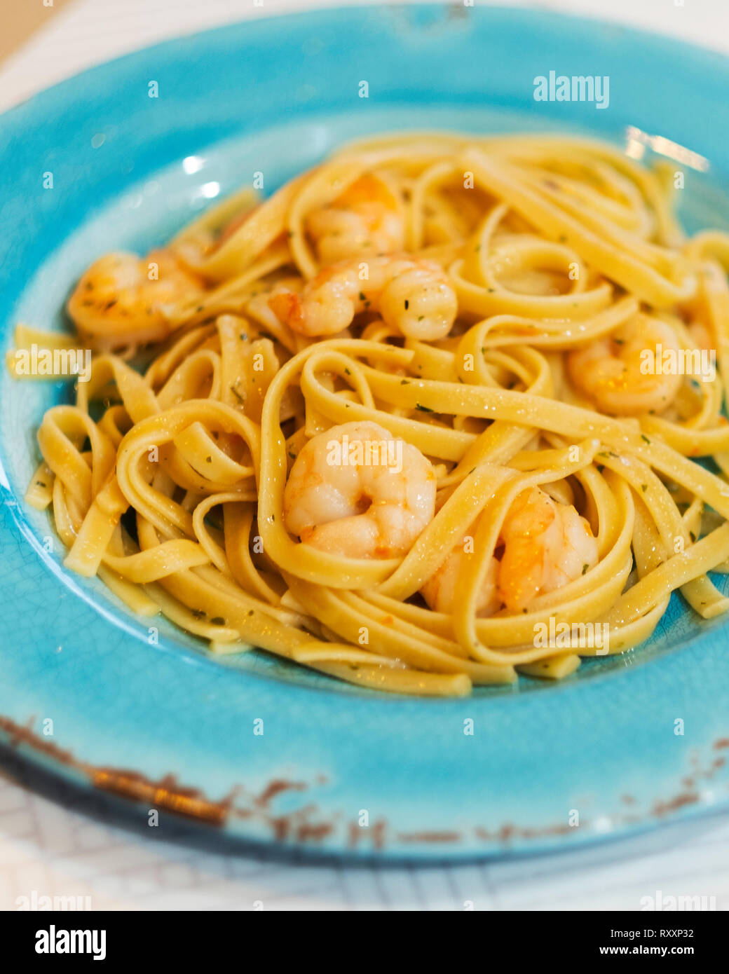 Shrimp Scampi über fetticchini Pasta serviert auf einem Aqua Platte. Stockfoto