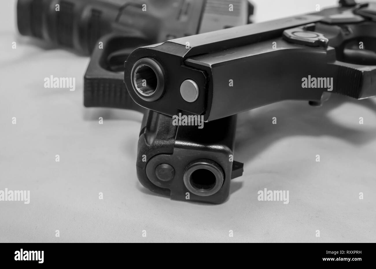 Zwei schwarze Pistolen, ein 9 mm und einen 40-Kaliber, eine auf der anderen auf weißem Hintergrund Stockfoto