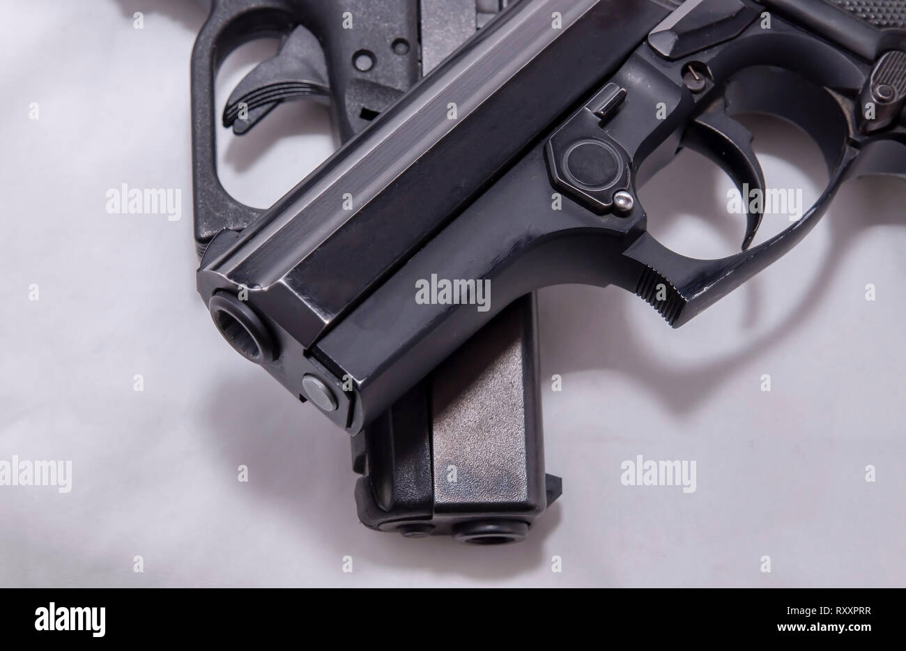 Zwei schwarze Pistolen, ein 9 mm und einen 40-Kaliber, eine auf der anderen auf weißem Hintergrund Stockfoto