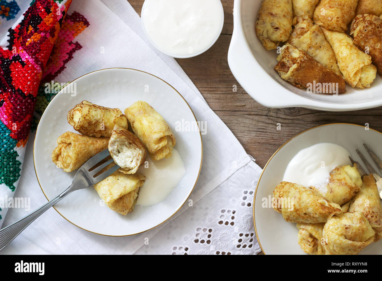 Hausgemachte Pfannkuchen gefüllt mit Hüttenkäse mit Rosinen, serviert mit saurer Sahne und Kirschen. Traditionelle moldawische oder rumänischen Dessert, selektive fo Stockfoto