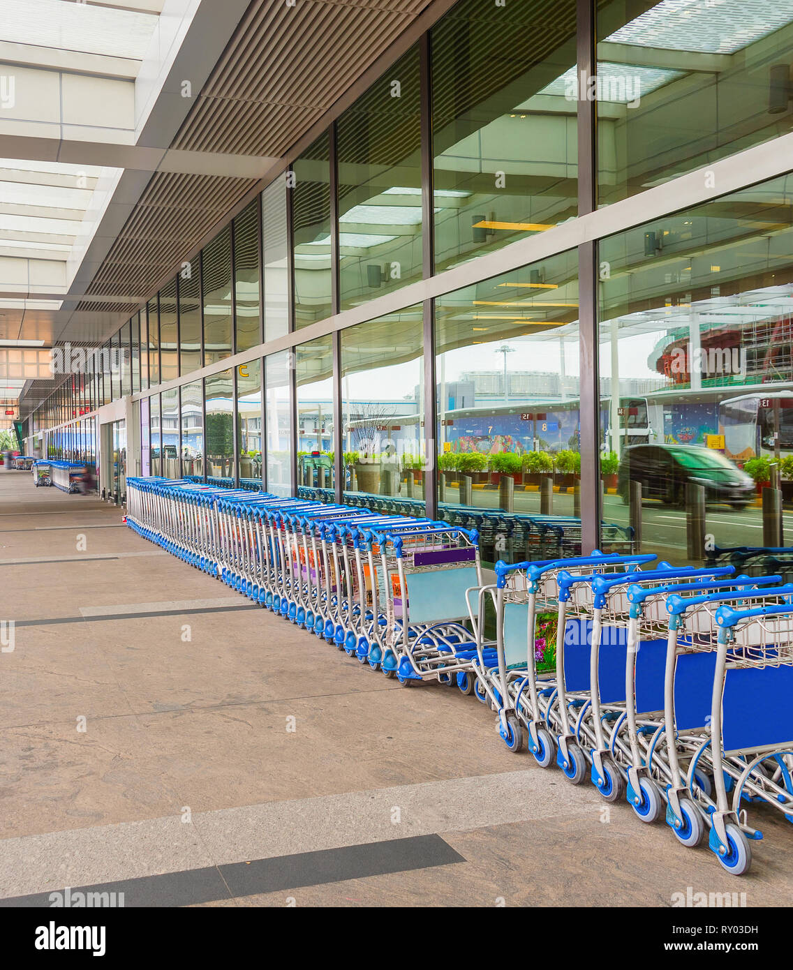 Reihen von Gepäckwagen vom Flughafen Singapur Eingang, Taxis in der Glasfassade reflektiert Stockfoto