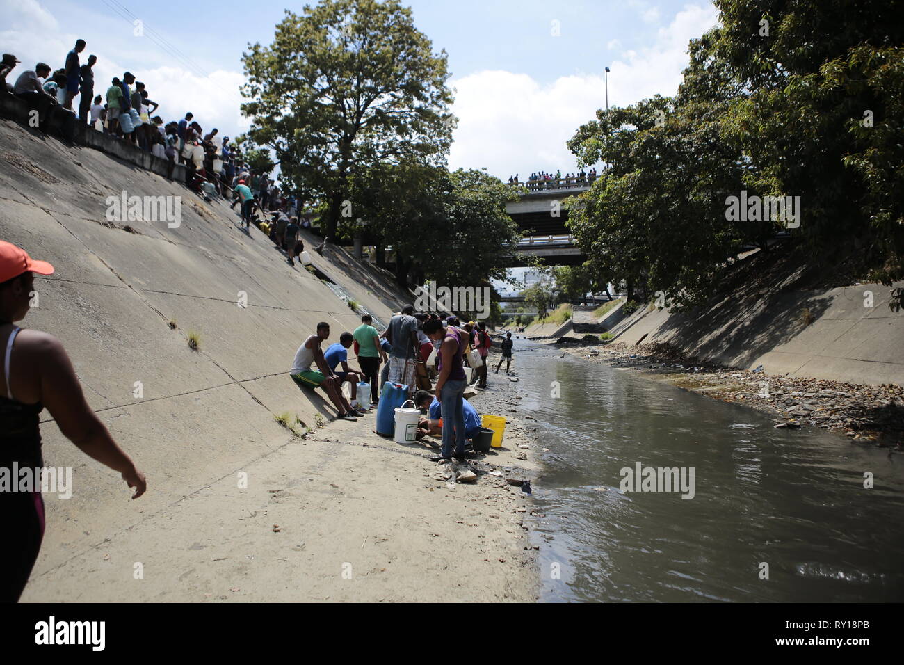 Caracas, Venezuela. 11 Mär, 2019. Viele Menschen warten in der Lage sein, Eimer und Wasser Kanister mit Wasser, fließt an einer Wand zu füllen. Aufgrund der massiven Stromausfall in Venezuela, viele Haushalte haben keine Wasserversorgung. Teile des Landes haben bereits von der Stromversorgung abgeschnitten worden seit 07.03.2019. Nach Ansicht der Opposition, ein Buschfeuer in der Nähe eine wichtige Hochspannungsleitung das Stromnetz zusammenbricht. Die sozialistische Regierung von Maduro, auf der anderen Seite warf eine Cyber Attack von den USA für den Stromausfall geplant. Credit: Rafael Hernandez/dpa/Alamy leben Nachrichten Stockfoto