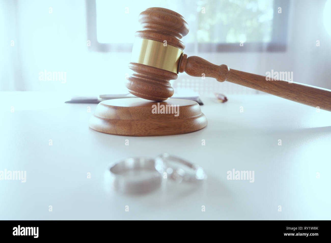 Trauringe und Hammer Richter Hammer auf Rechtsanwalt Schreibtisch für Familie Trennung, Scheidung Konzept Stockfoto