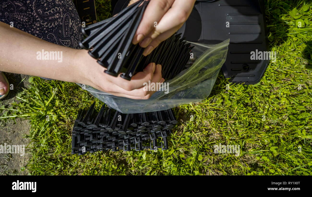 Die schwarze Klinge Teile der Rasenmäher aus einer Plastiktüte auf dem Rasen angeordnet Stockfoto