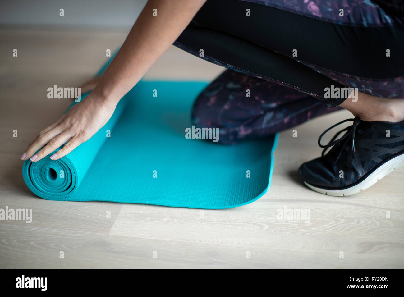 Nahaufnahme von Frau Rolling Out Trainingsmatte auf dem Boden vor dem Training Stockfoto