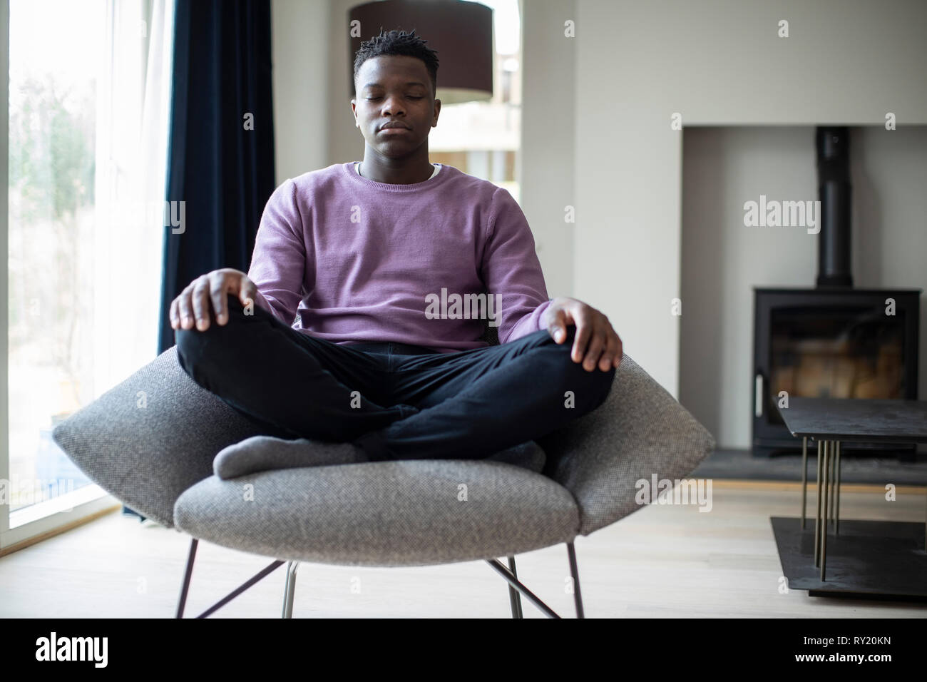 In der Nähe von ruhigen Teenager Meditieren sitzt im Sessel zu Hause Stockfoto