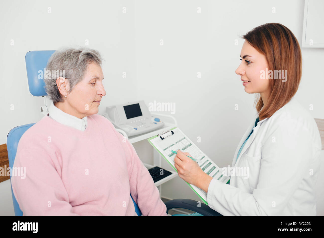 Arzt Überprüfung der medizinischen Chart mit Ihrer älteren Patienten an medizinischen Zimmer Stockfoto