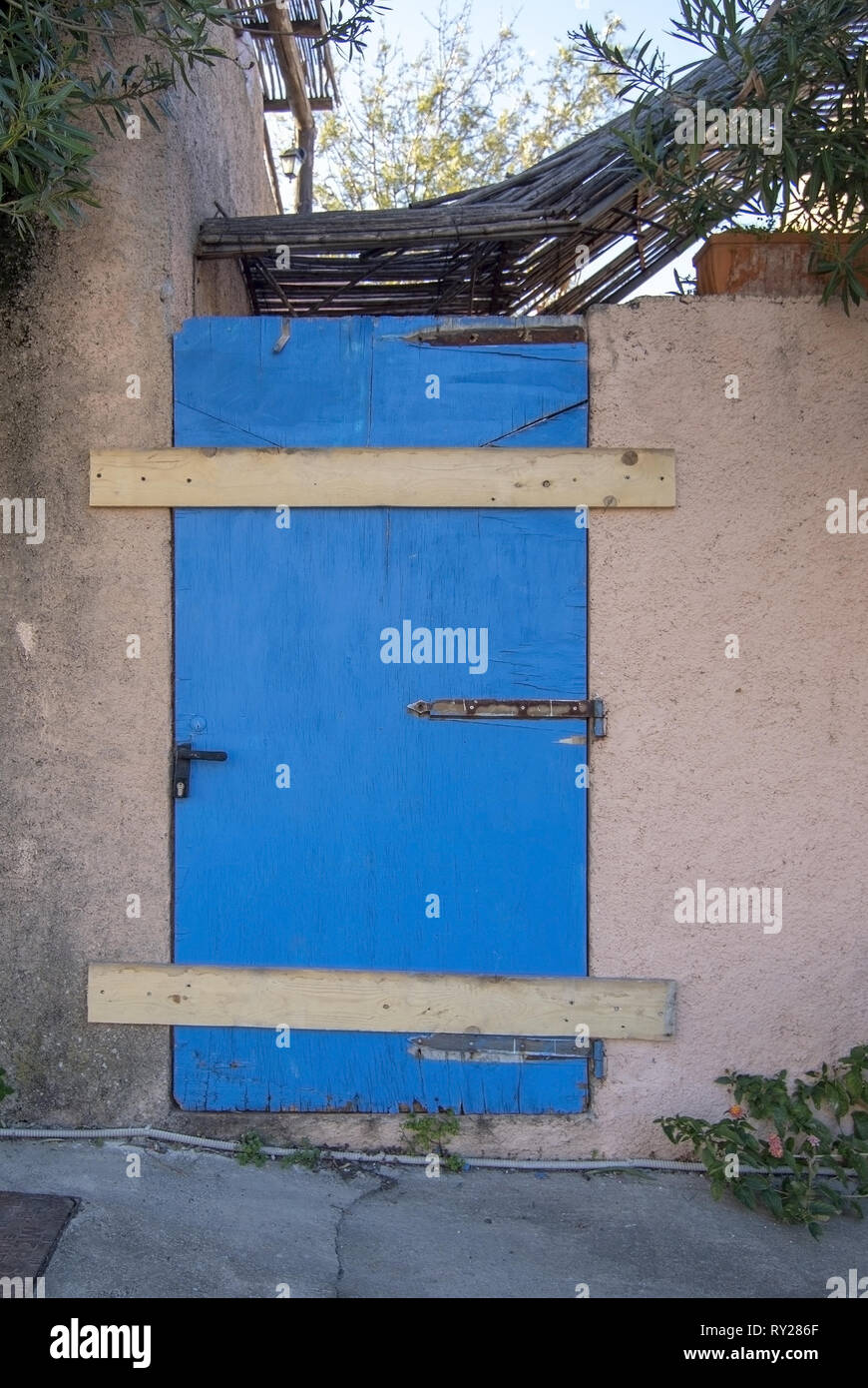 Alte, verwitterte Tür blau lackiert geschlossen mit Holzplatten nicht verfügbar geschlossenes Konzept Stockfoto